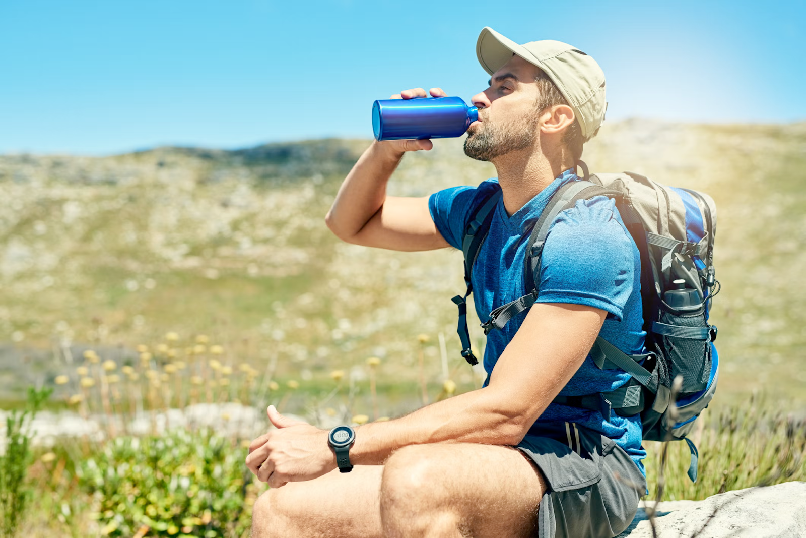 A man in trekking attire, taking break by drinking some water