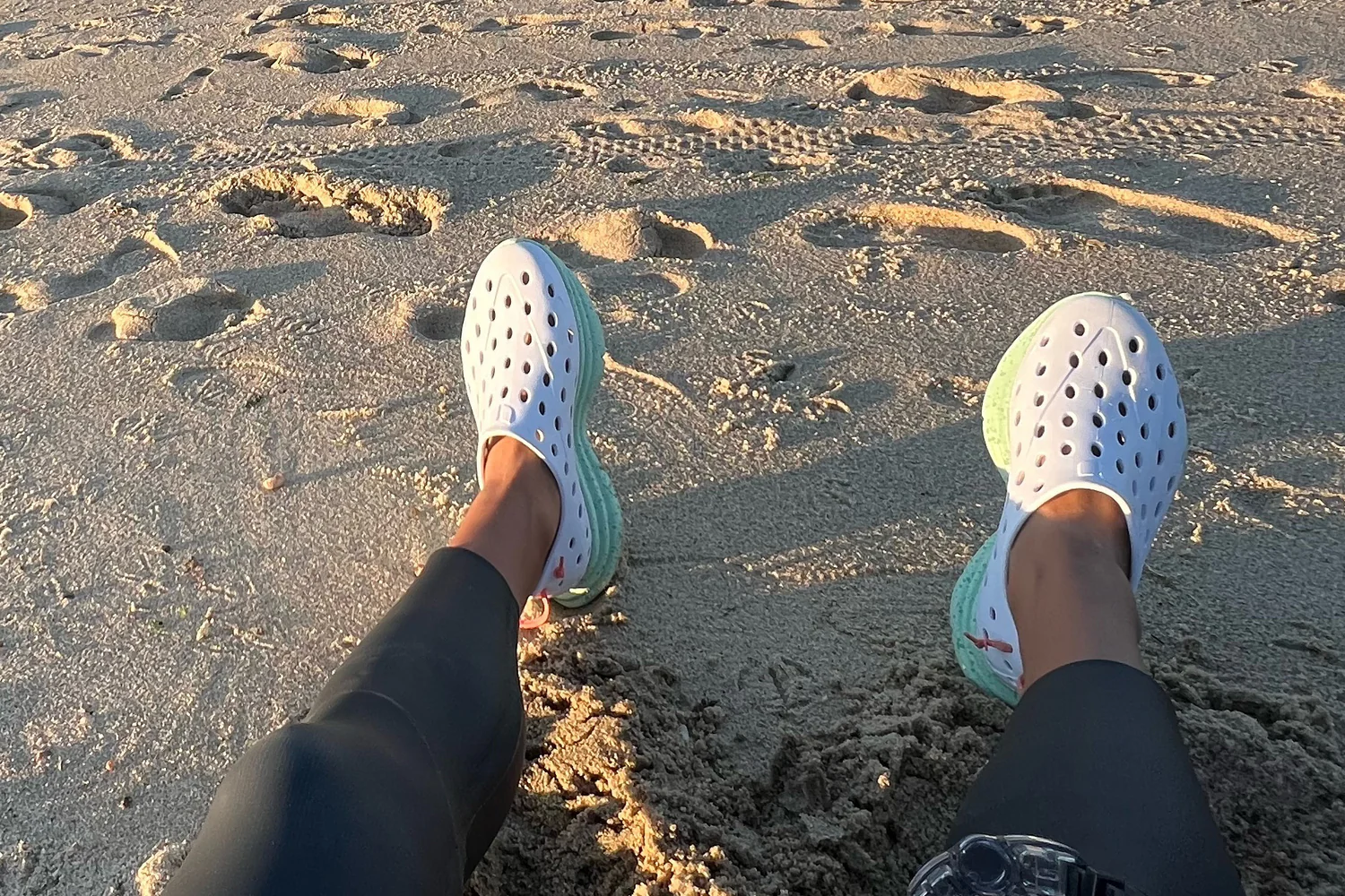 A person wearing croc shoes on the sand