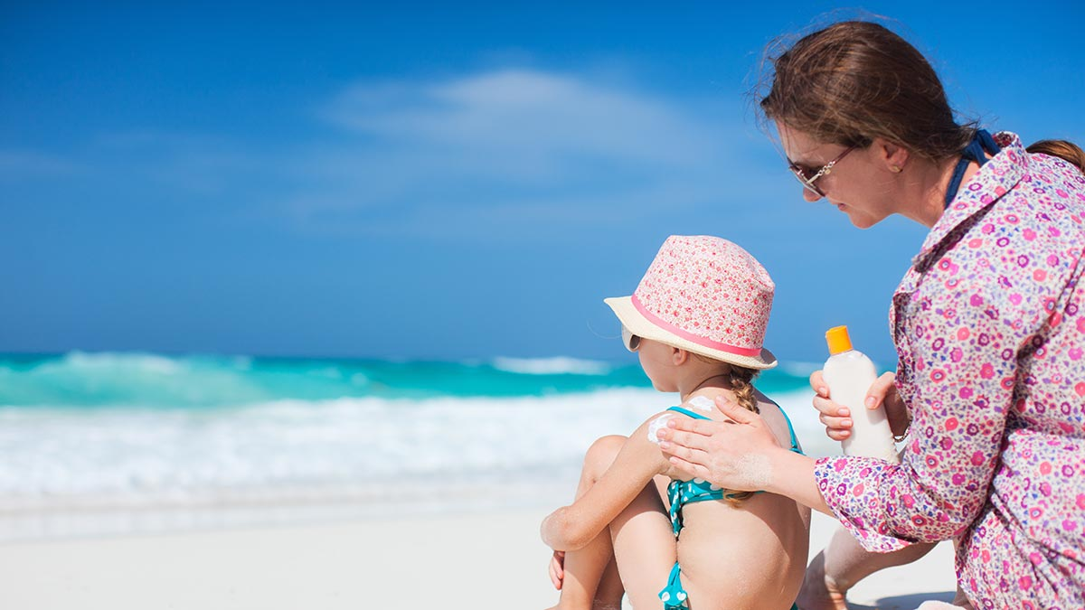 A woman applying sunshine to her child on a beach